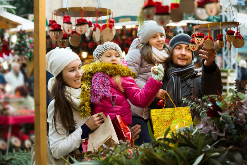 Family shopping at outdoor holiday market.