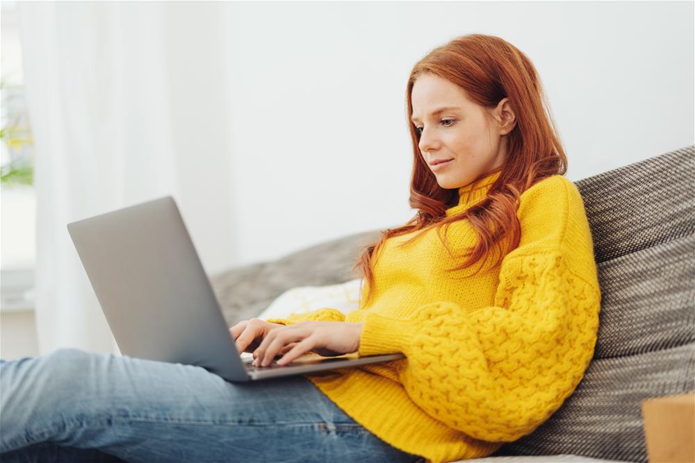 sitting on couch looking at laptop sitting on couch looking at laptop