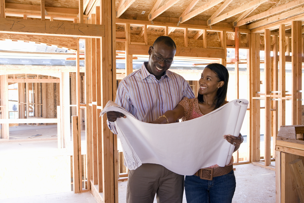 Couple looking at blueprint in newly constructed home.
