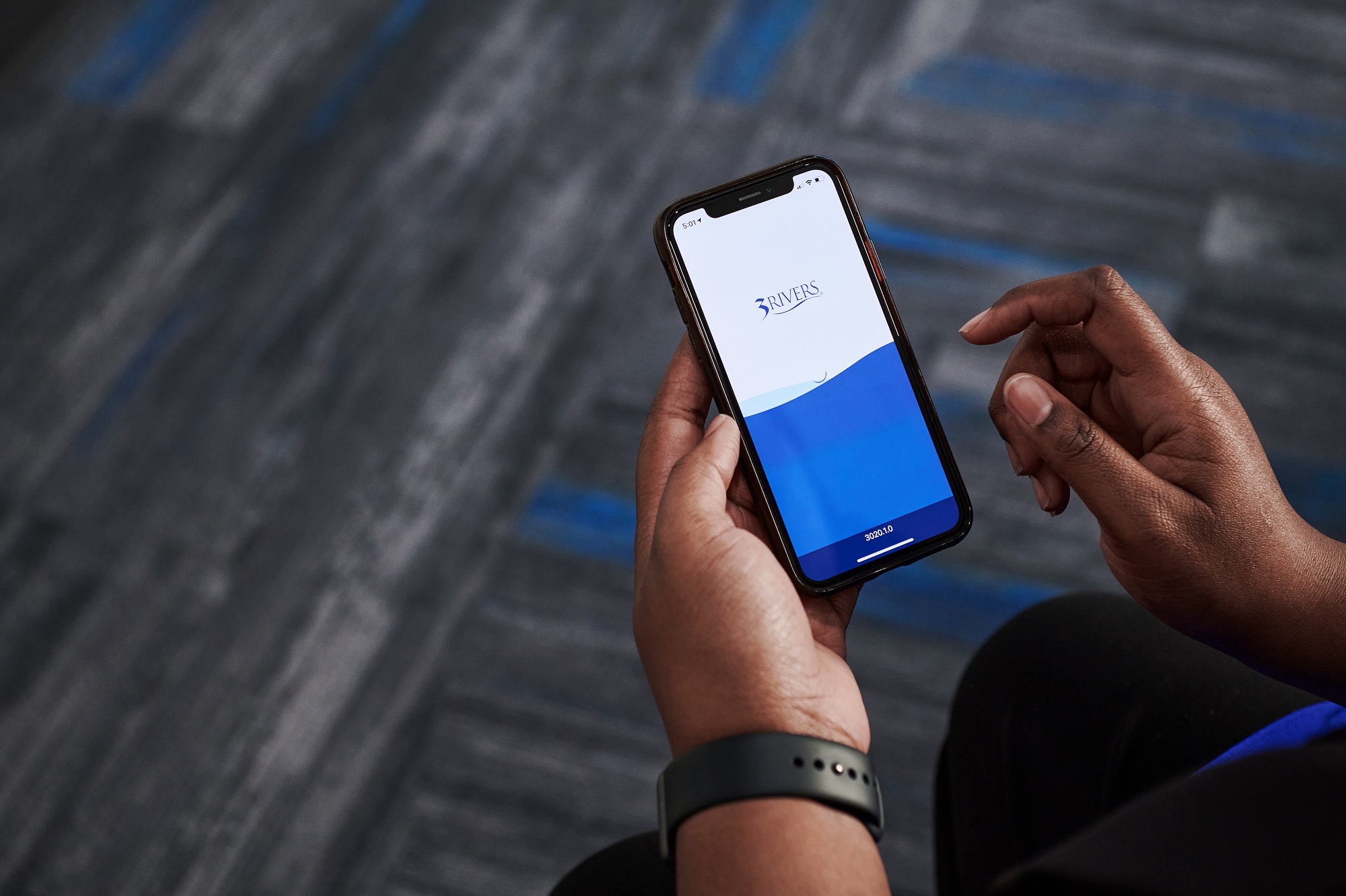 A close-up of a mobile phone featuring the 3Rivers mobile banking app launch screen.