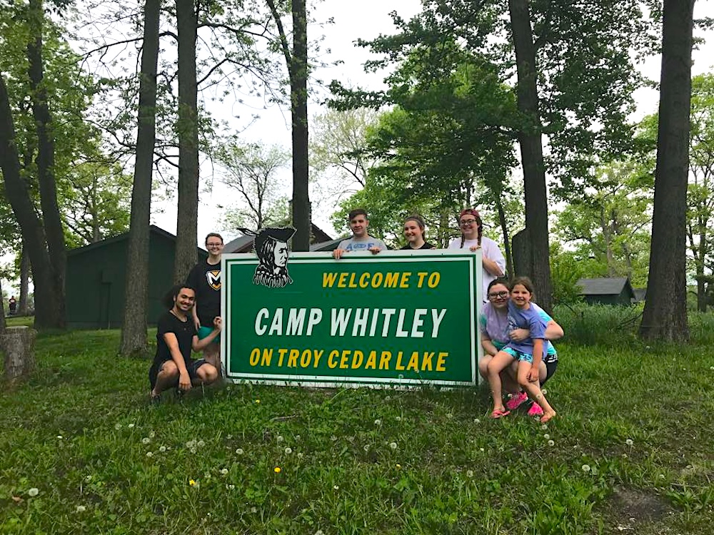 People standing around the Camp Whitley sign at Camp Whitley