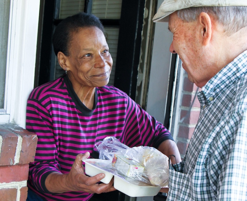 A volunteer delivering food to someone's home.