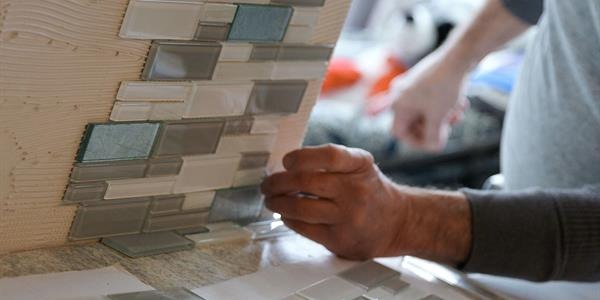 A person putting tile in their kitchen