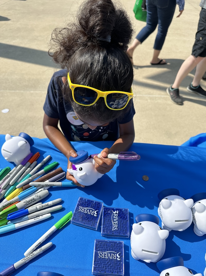 A child decorates a 3Rivers piggy bank at PBS Explorer Day in 2023.