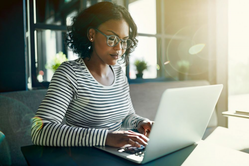 Woman on laptop computer in office with sun shining in.