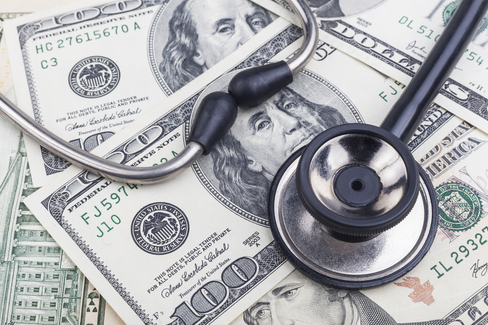 Stethoscope on top of US hundred dollar bills.