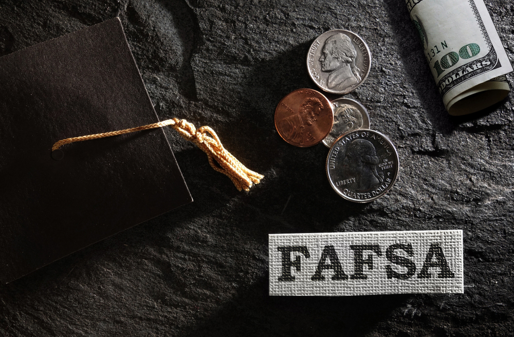Graduation cap and money next to FAFSA sign