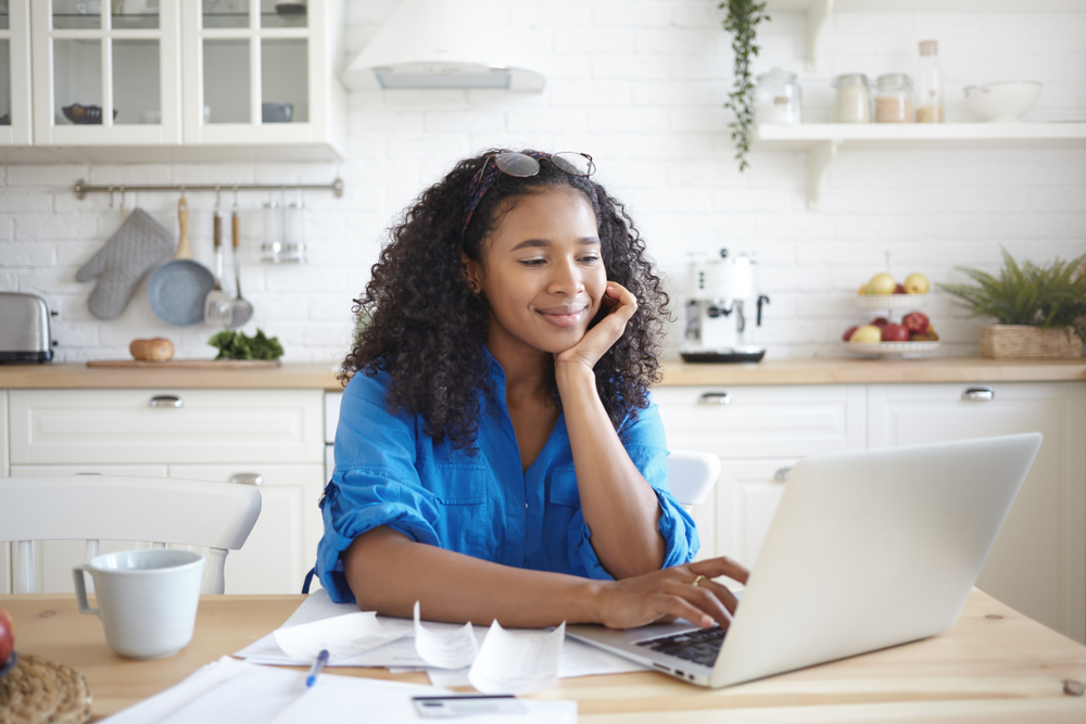 Woman using laptop computer in kitchen.