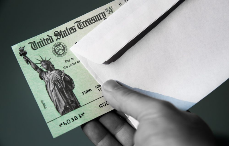 Close up of hand holding a United States Treasury check.