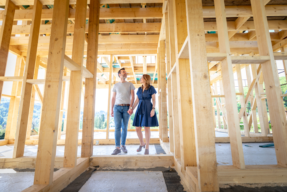 Young couple walking through framework of house.