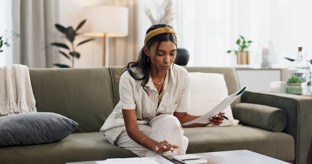 Woman on couch using calculator