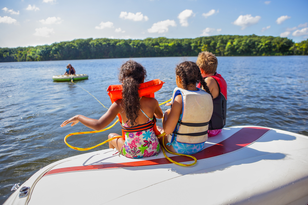 Kids sitting on a boat in a lake.