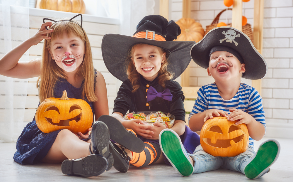 Three kids dressed in Halloween costumes.
