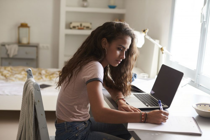 Young female working on a paper at desk.