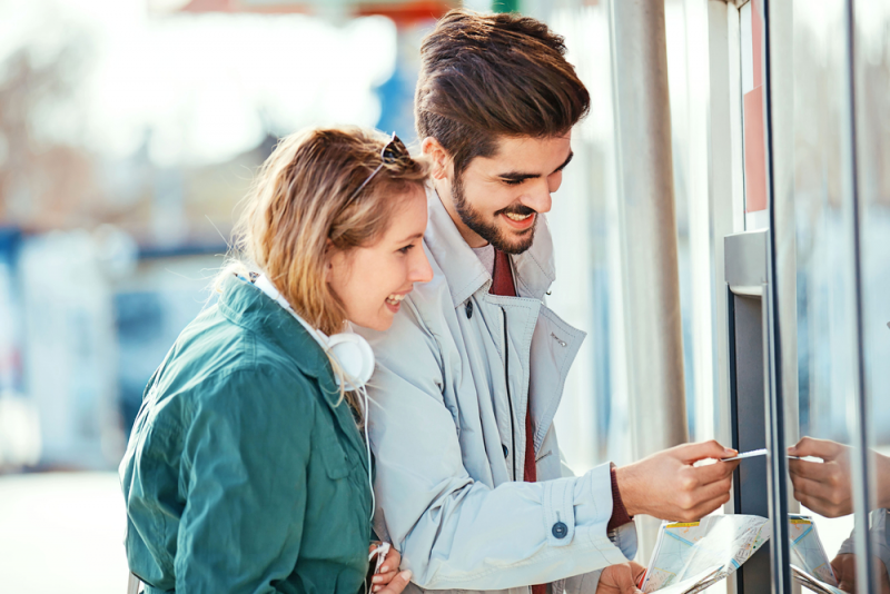 Man and woman inserting card into ATM.