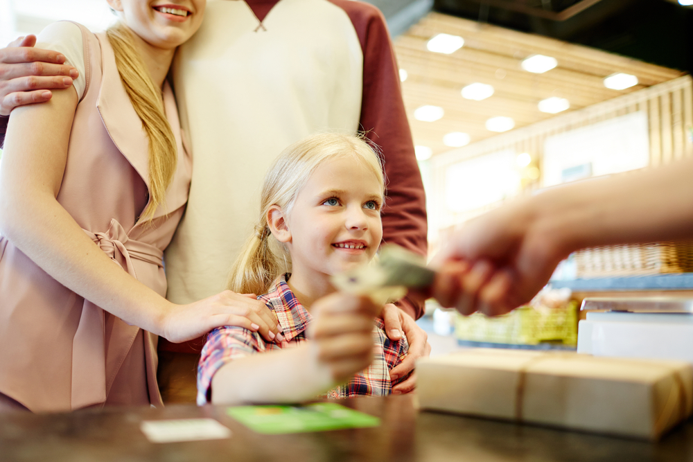 Young child handing cashier money.