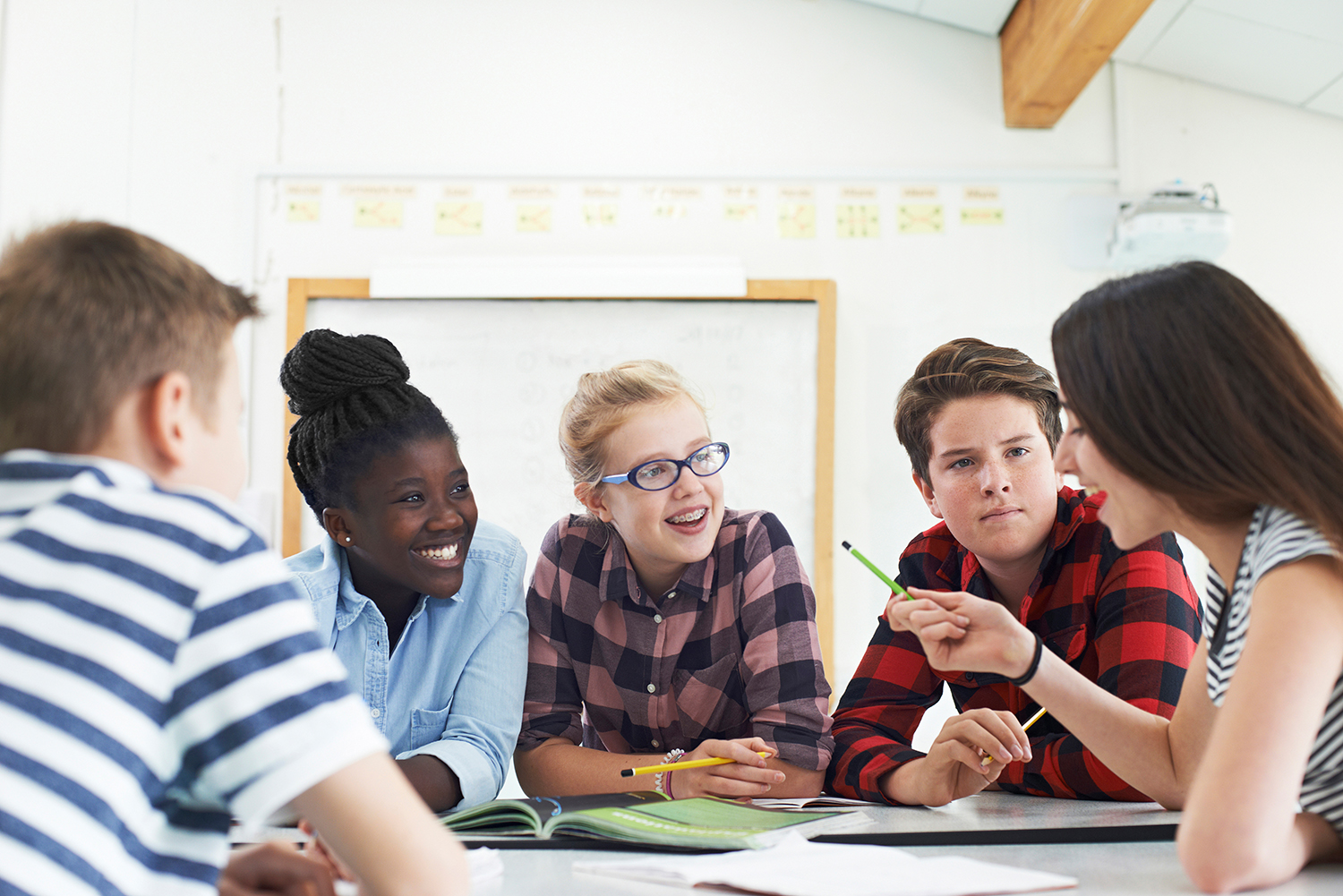 Middle school students talking in classroom.