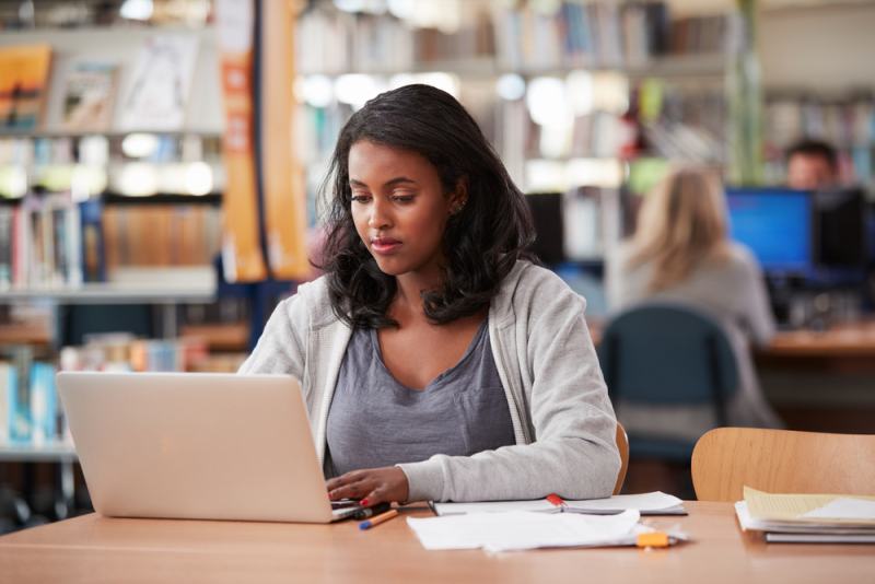 Young woman using a laptop in library.