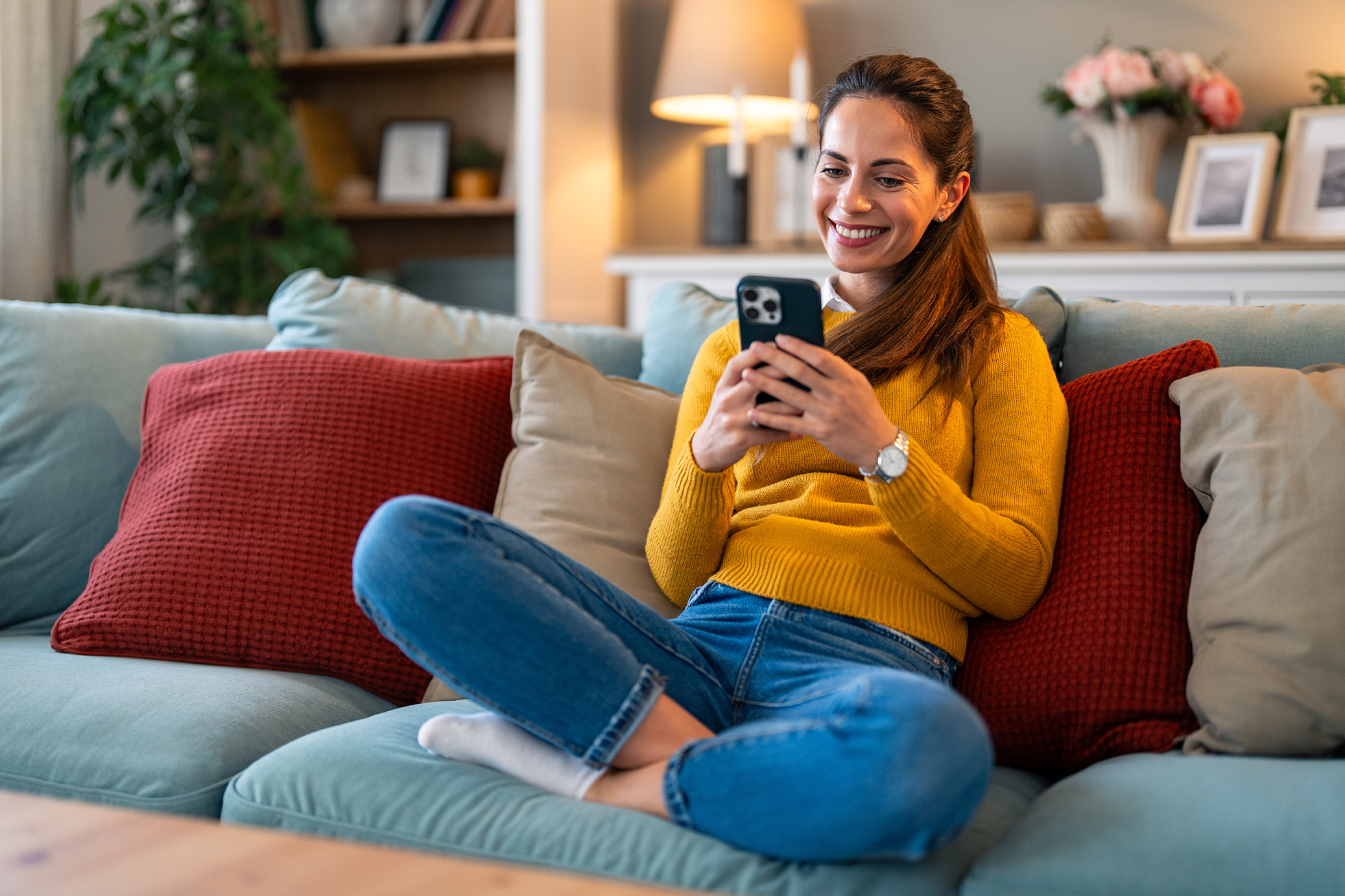 Woman on couch smiling and looking at her phone