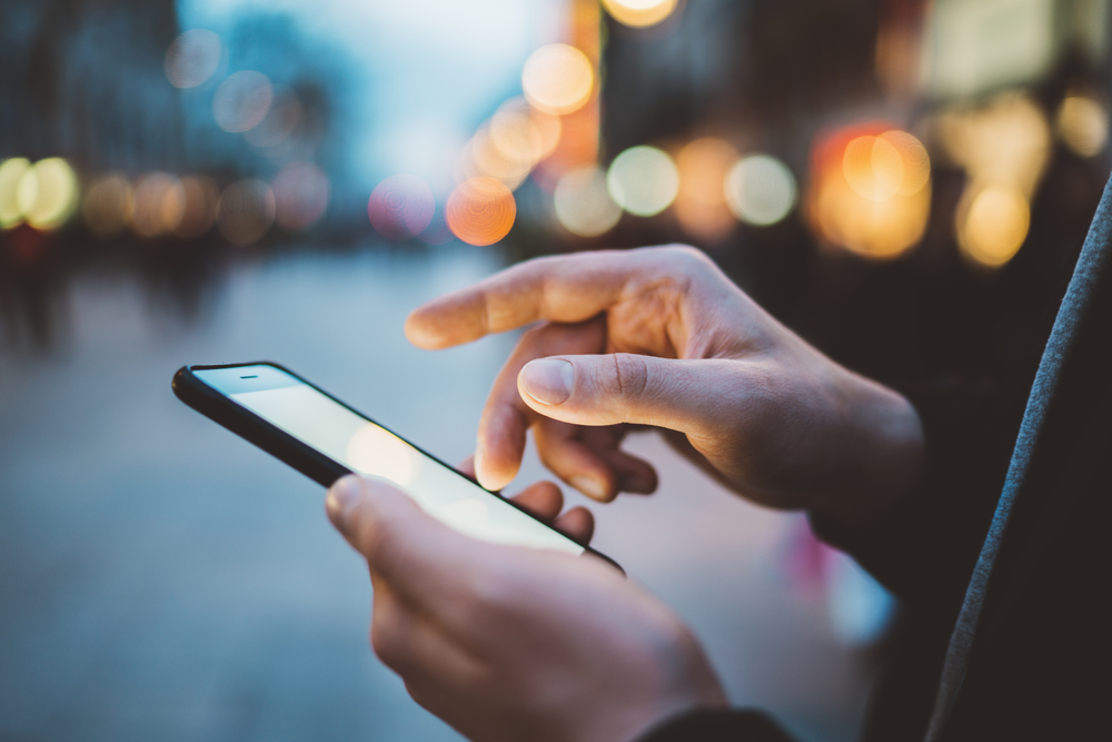 Close up of hands holding a mobile phone.